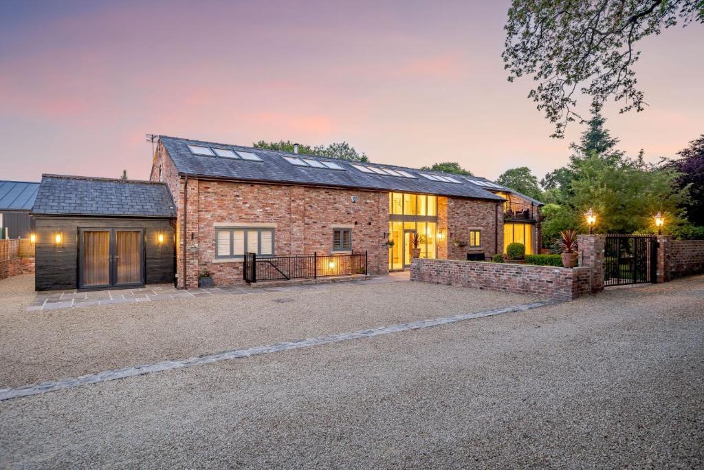 a brick house with a driveway in front of it at Skyfall in Prestbury