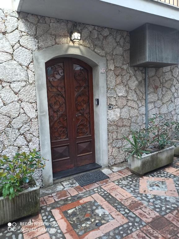 uma porta de madeira num edifício de pedra com duas plantas em MEDUSA house em Taormina