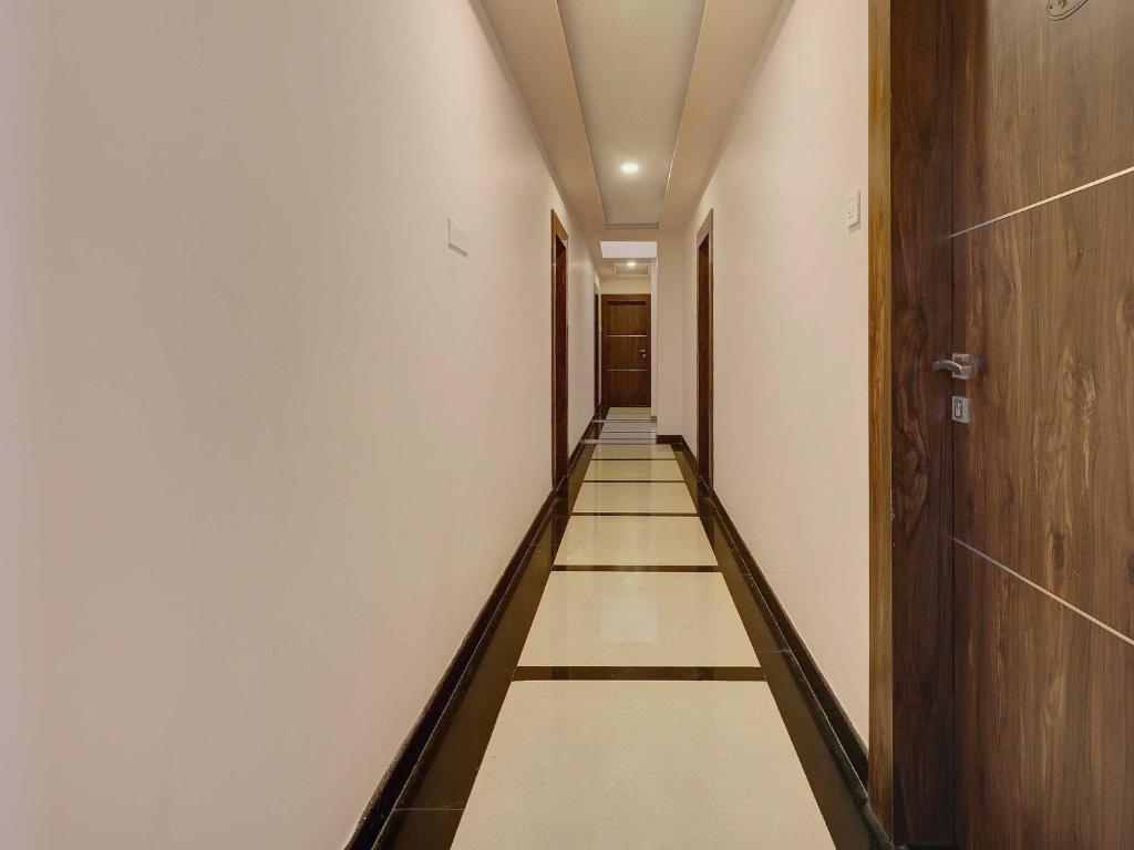 a long corridor with white walls and floors and a wooden door at Bhagirathi Residency in Anantapur
