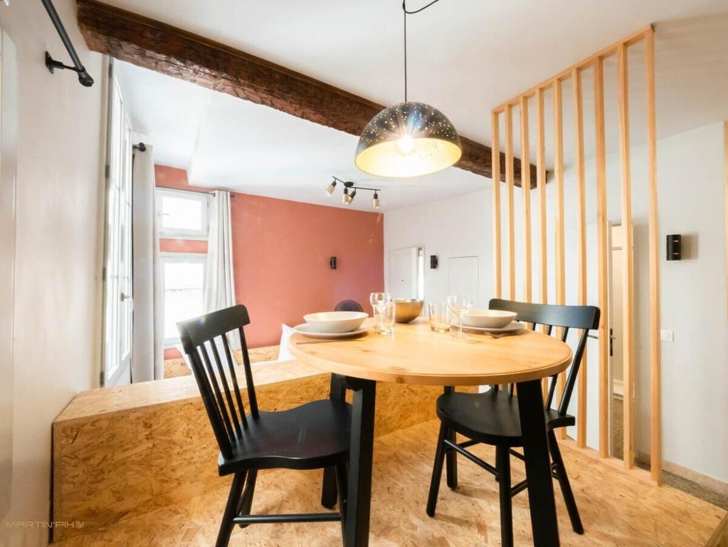 uma sala de jantar com uma mesa de madeira e cadeiras em Le hollandais - Cœur de ville em Montpellier