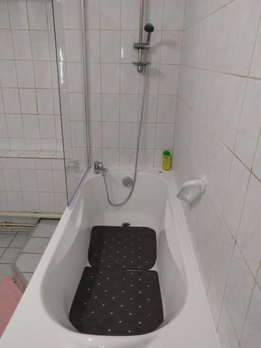 a bath tub with a black seat in a bathroom at Confortable appart 5 mins centre de valenciennes in Anzin