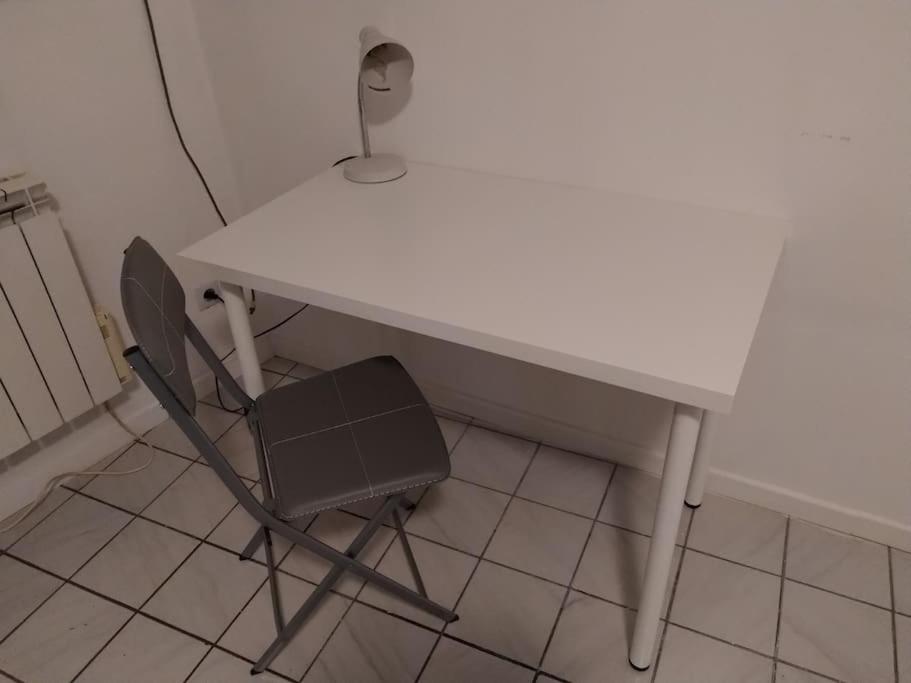 a white table and a chair in a room at Confortable appart 5 mins centre de valenciennes in Anzin