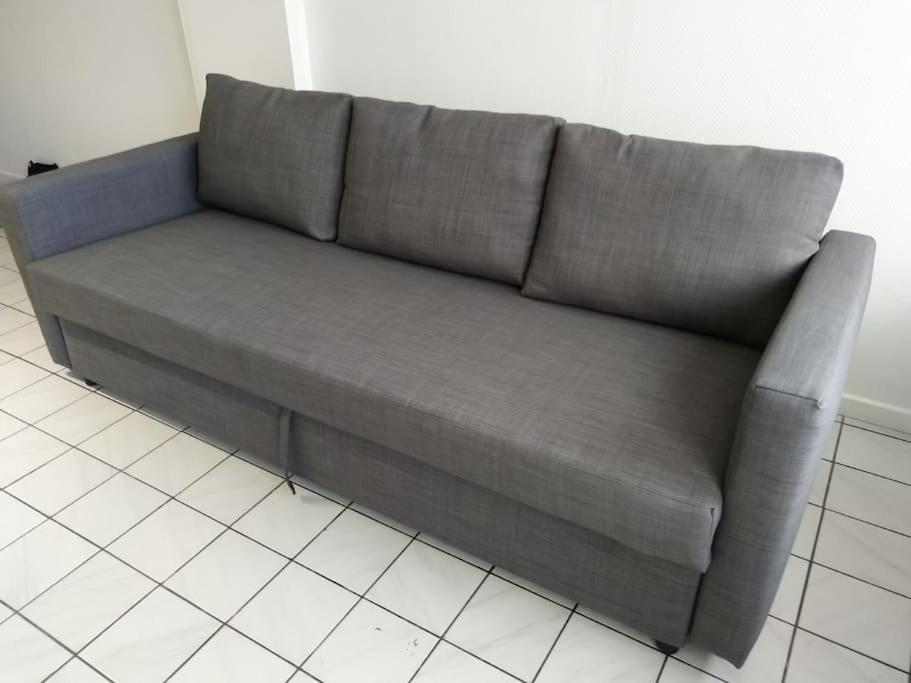 a gray couch sitting in a living room at Confortable appart 5 mins centre de valenciennes in Anzin