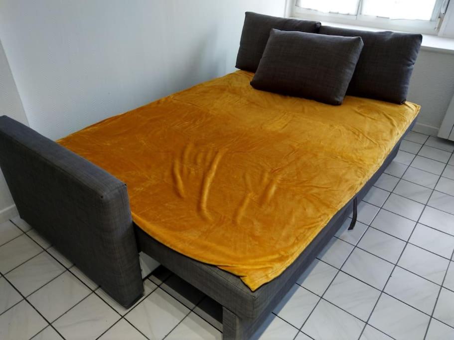 a bed with a yellow blanket on top of it at Confortable appart 5 mins centre de valenciennes in Anzin