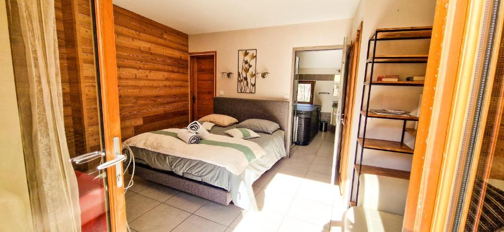 1 dormitorio con 1 cama y pared de madera en Les Clarines Perceneige - Chambre d'Hôtes Vue Sur Montagne, en Saint-Jacques-en-Valgodemard