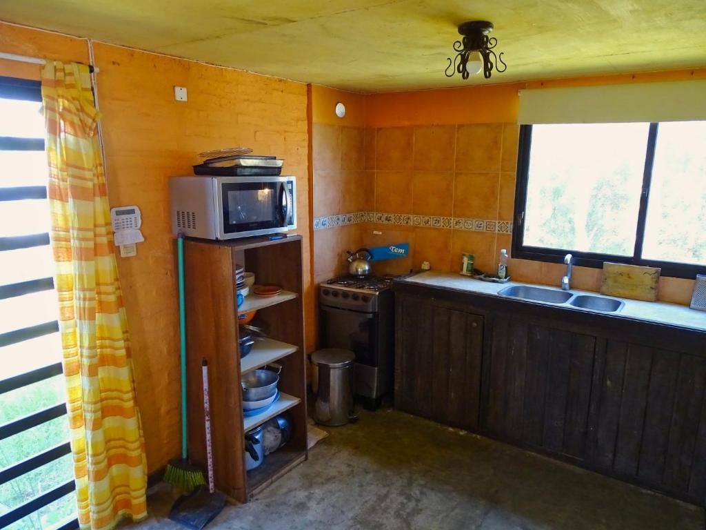 a small kitchen with a sink and a microwave at Casa Amarilla con Jacuzzi in Punta Del Diablo