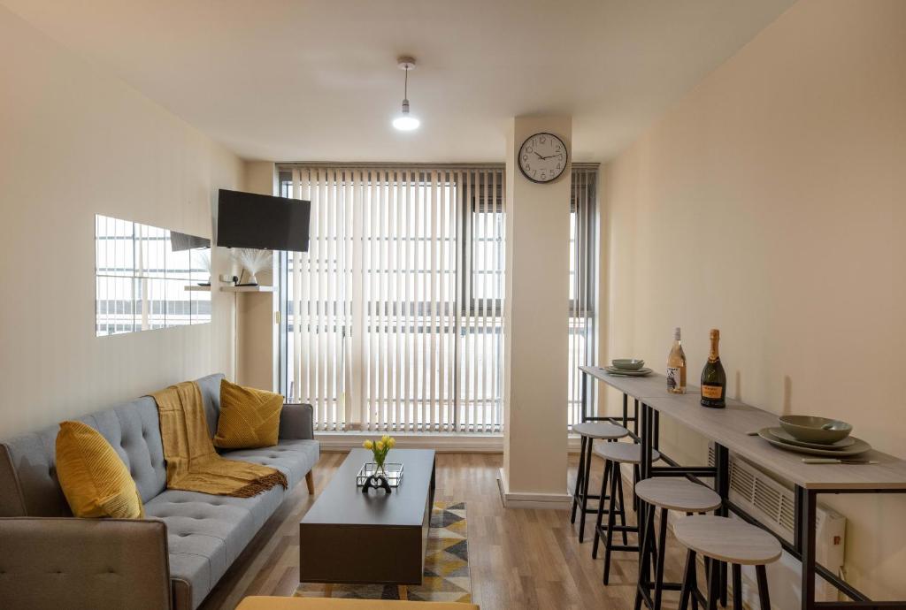 a living room with a couch and a bar with stools at Grand Central , 2 double bedroom apartment with free parking , Birmingham in Birmingham