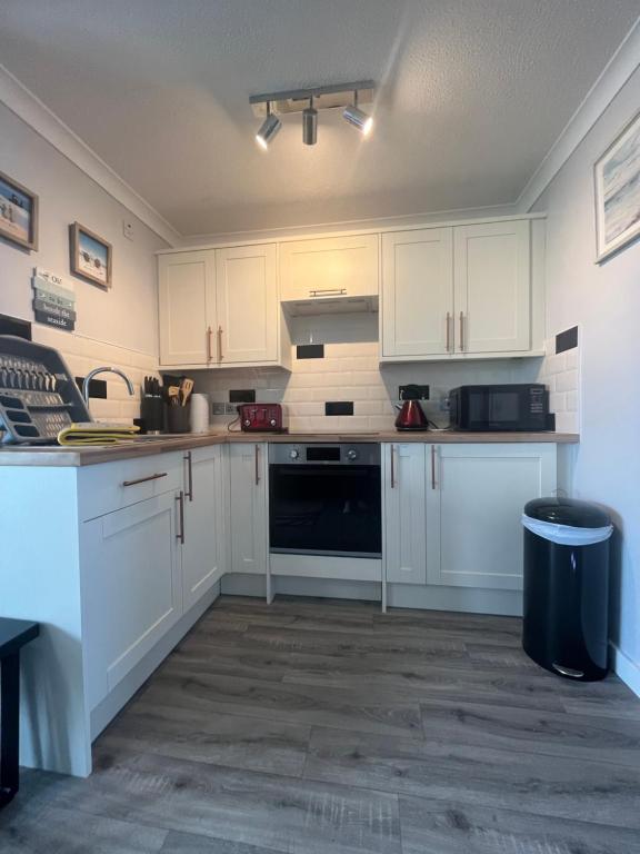 a kitchen with white cabinets and a black appliance at 246, Belle Aire, Hemsby - Beautifully presented two bed chalet, sleeps 5, pet friendly, close to beach! in Great Yarmouth