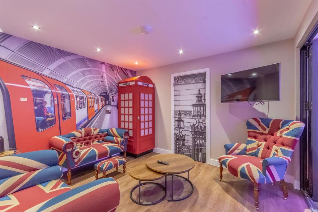 The Old School House - Luxury Themed Apartments في نوتينغهام: غرفة مع قطار مع كراسي وكابينة هاتف