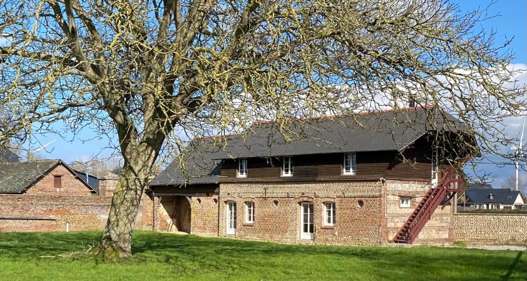 un bâtiment en briques avec un toit noir et un arbre dans l'établissement Gite de Beaufournier, à Avremesnil