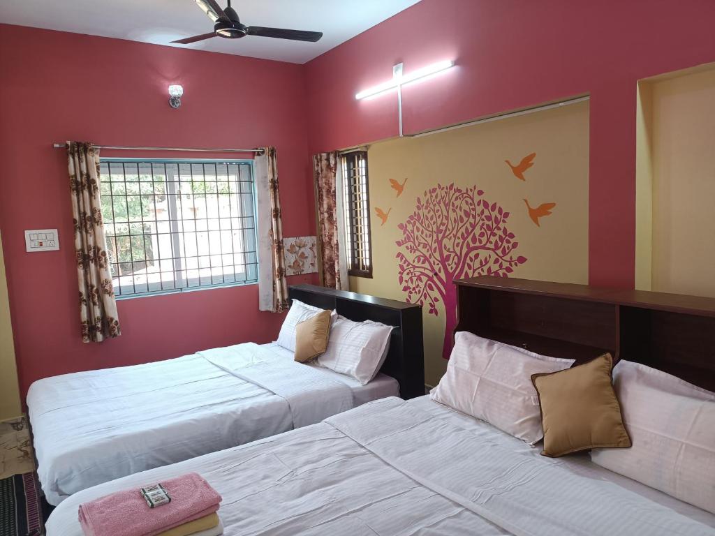 2 camas en una habitación con paredes rojas en Guru Residency Pondicherry, en Pondicherry