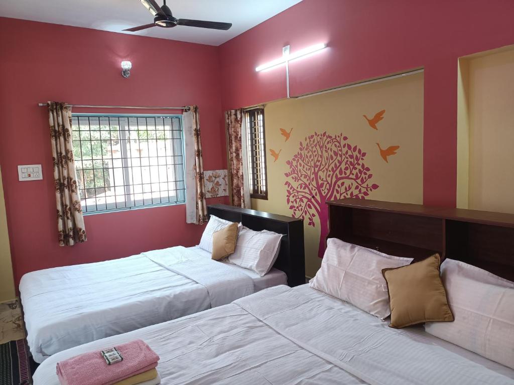 two beds in a room with red walls at Guru Residency Pondicherry in Puducherry