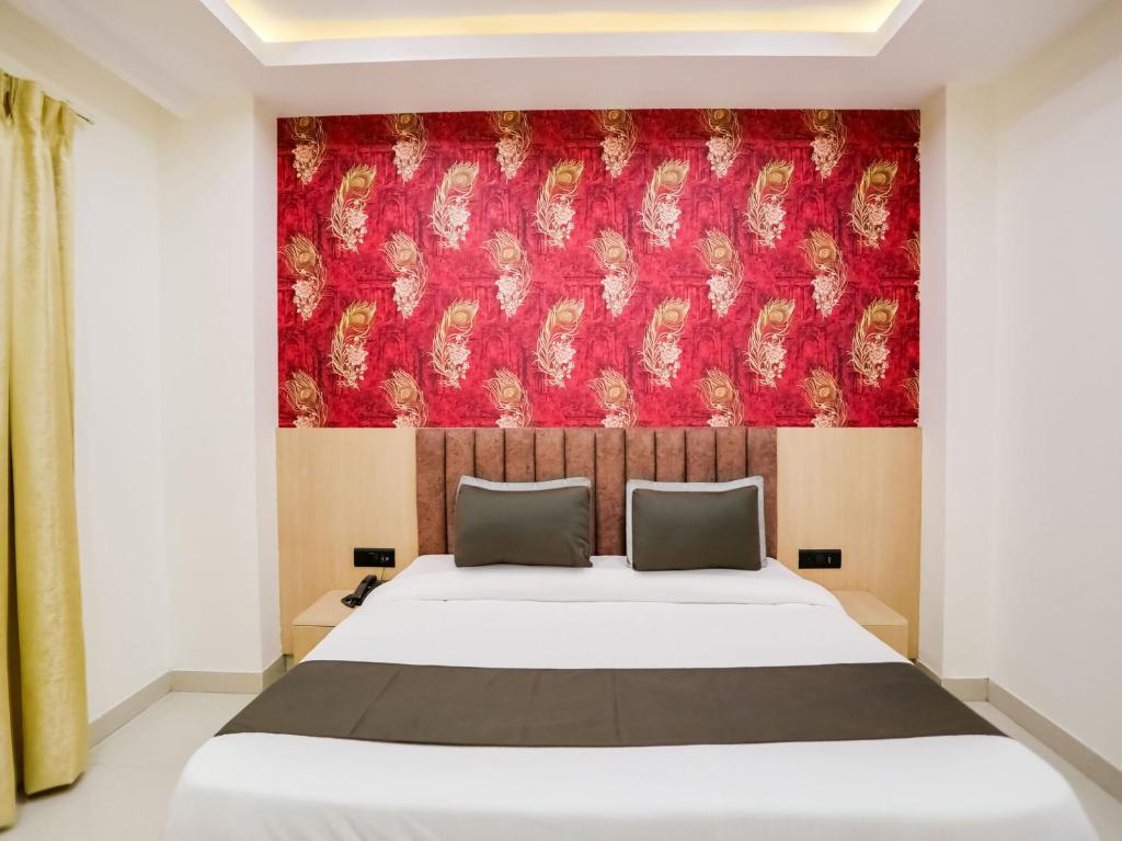 1 dormitorio con cama y pared roja en Super Townhouse 1288 Magnolia Corporate Stays, en Gurgaon