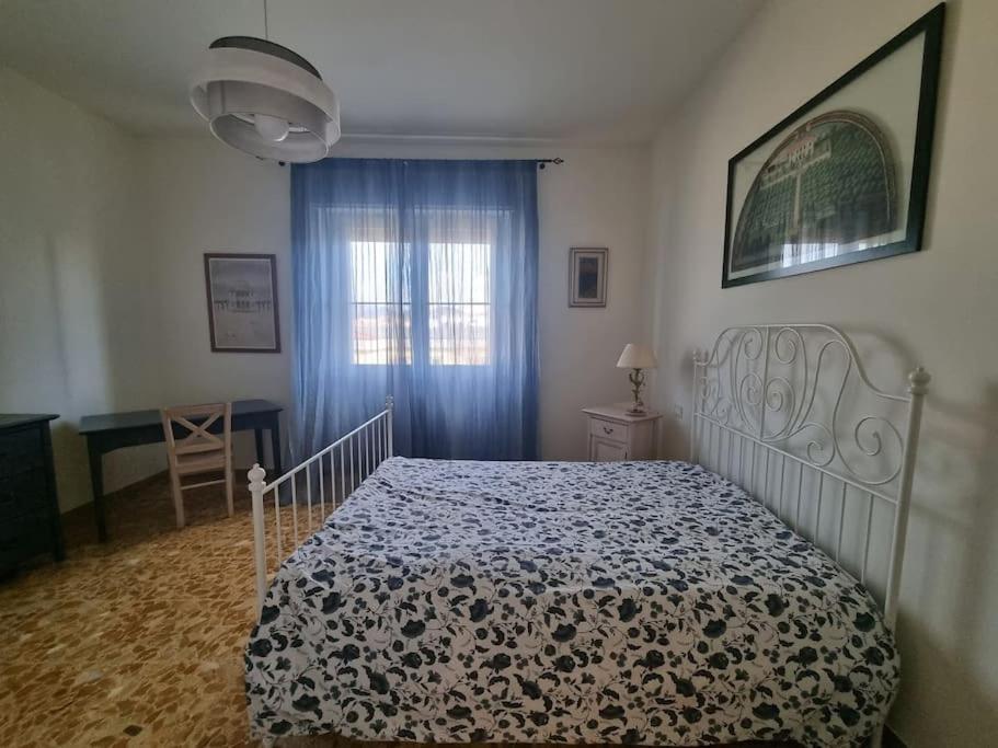 a bedroom with a bed and a window and a table at LC e i 7 nani in Pisa