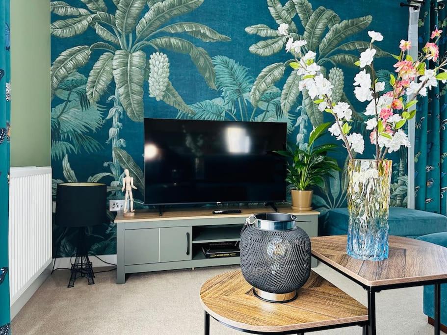 a living room with a tv and a vase of flowers on a table at Cosy apartment at the marina in Portishead