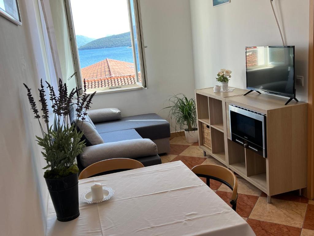 a living room with a couch and a tv and a table at Apartments and Rooms Katija & Egon in Korčula