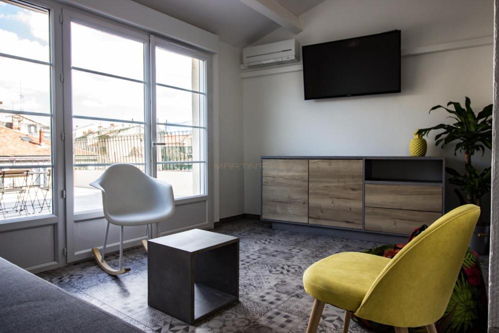 un salon avec une télévision, un canapé et des chaises dans l'établissement L'amoureux - terrasse et climatisation coeur de ville, à Montpellier