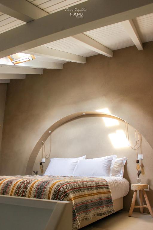 a bedroom with a large bed with an arch above it at Nomad Houses - Casa Sarilho in Beja