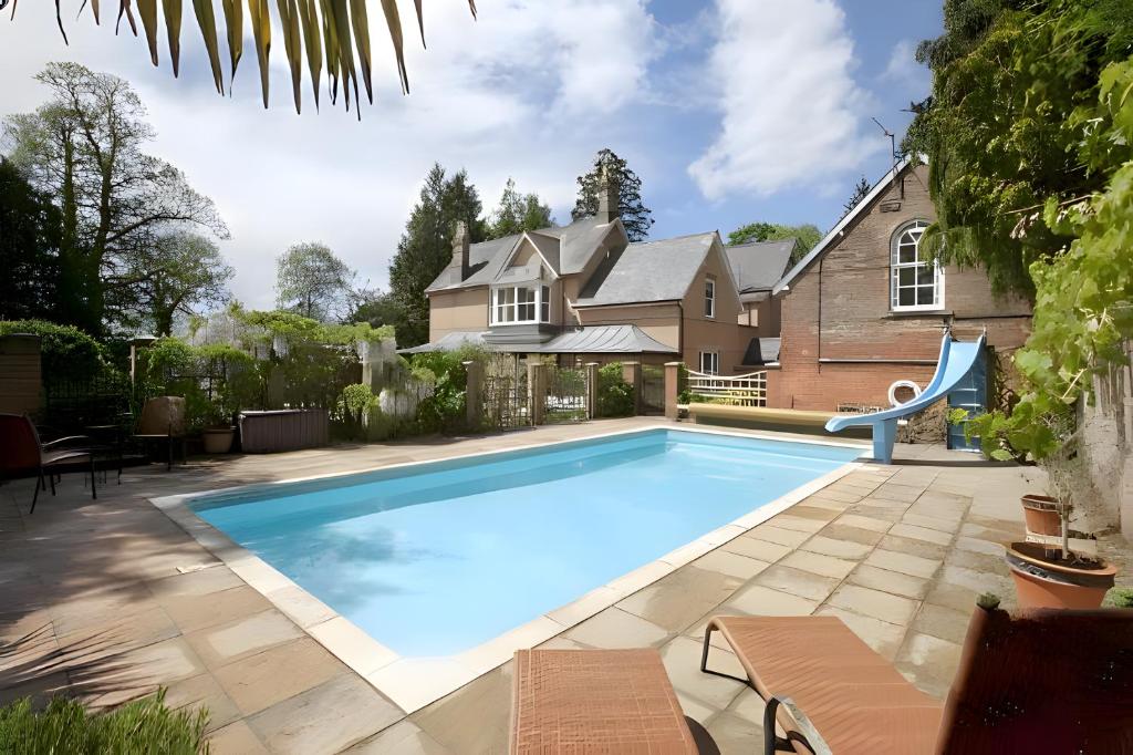 una piscina di fronte a una casa di Garth Lodge with Tennis Court and Pool a Wimborne Minster