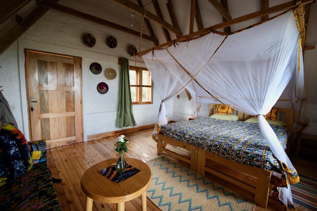 a bedroom with a canopy bed and a table at Hyena Hill Lodge in Sanga