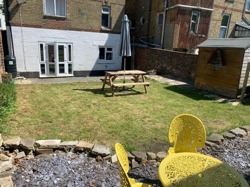 a patio with two chairs and an umbrella and a table at Ryde Beach Garden Apartment in Ryde