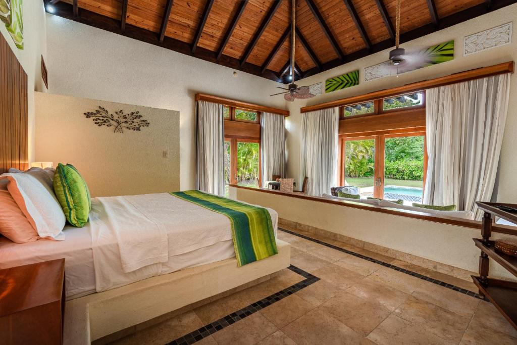 um quarto com uma cama num quarto com janelas em Newly added Tropical Bungalow at Green Village em Punta Cana