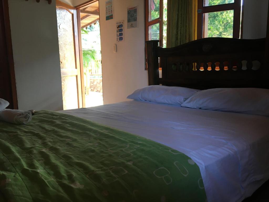a bedroom with a large bed and a window at Hostal Los Wichos in Minca