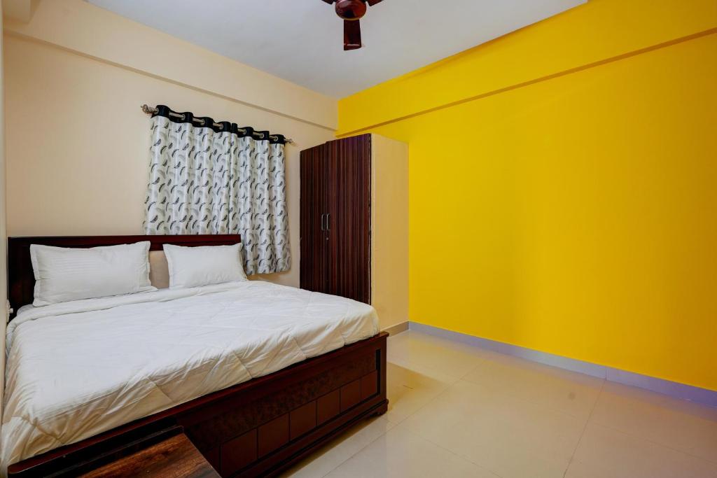 a bedroom with a bed with a yellow wall at OYO Hotel SD in Bangalore