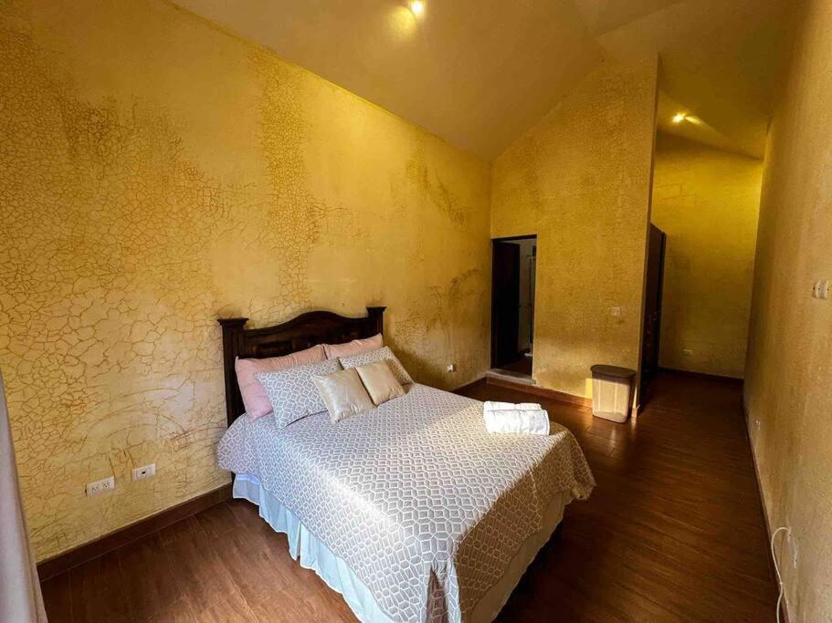 1 dormitorio con cama y pared amarilla en Villa Italiana, a 5min de Antigua, en San Lorenzo El Cubo