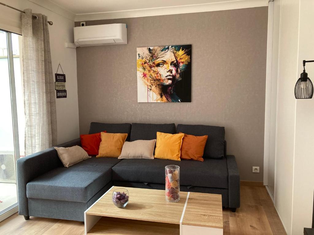 un salon avec un canapé bleu et un tableau dans l'établissement STUDIO à 50 mètres de la plage, à Antibes