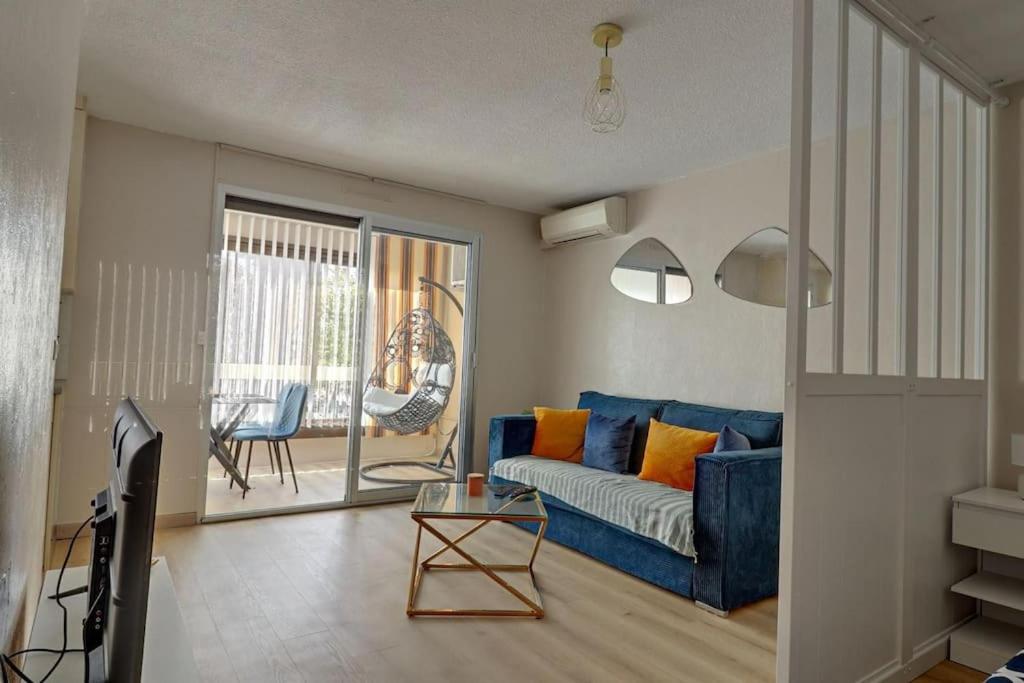 un salon avec un canapé bleu et une table dans l'établissement Esterel Plage I Bord de mer Fréjus I Clim I 4 personnes, à Fréjus