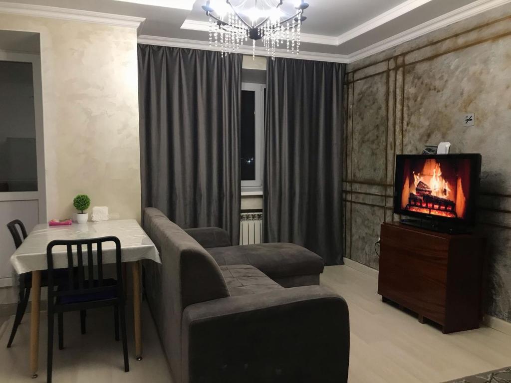sala de estar con TV, mesa y sillas en Апартаменты в районе Болашак, en Aktobe