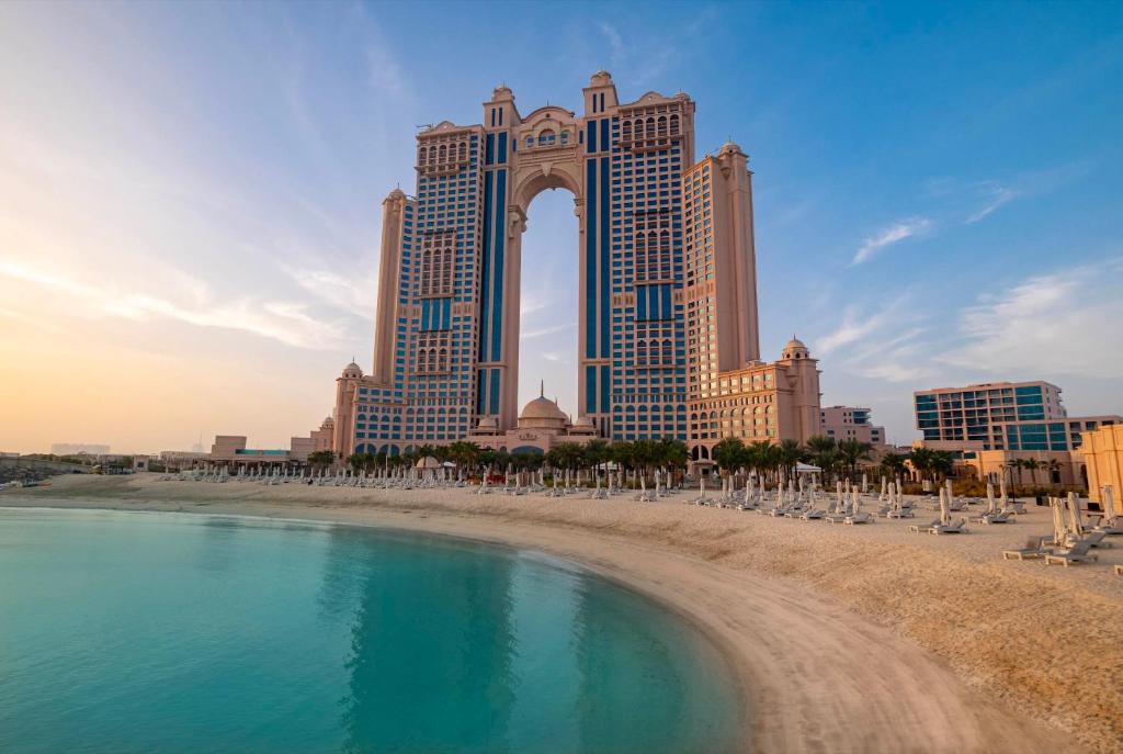 a beach in front of a hotel with a large tower at Fairmont Marina Abu Dhabi in Abu Dhabi