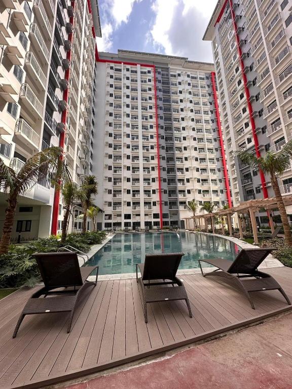a large building with a swimming pool and two chairs at Paranaque Manila Bloom residences in Manila