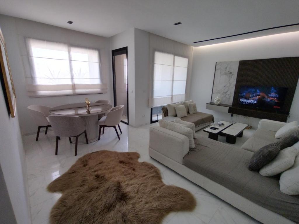 a living room with a couch and a table and a tv at Appartement Californien in Sidi Daoud
