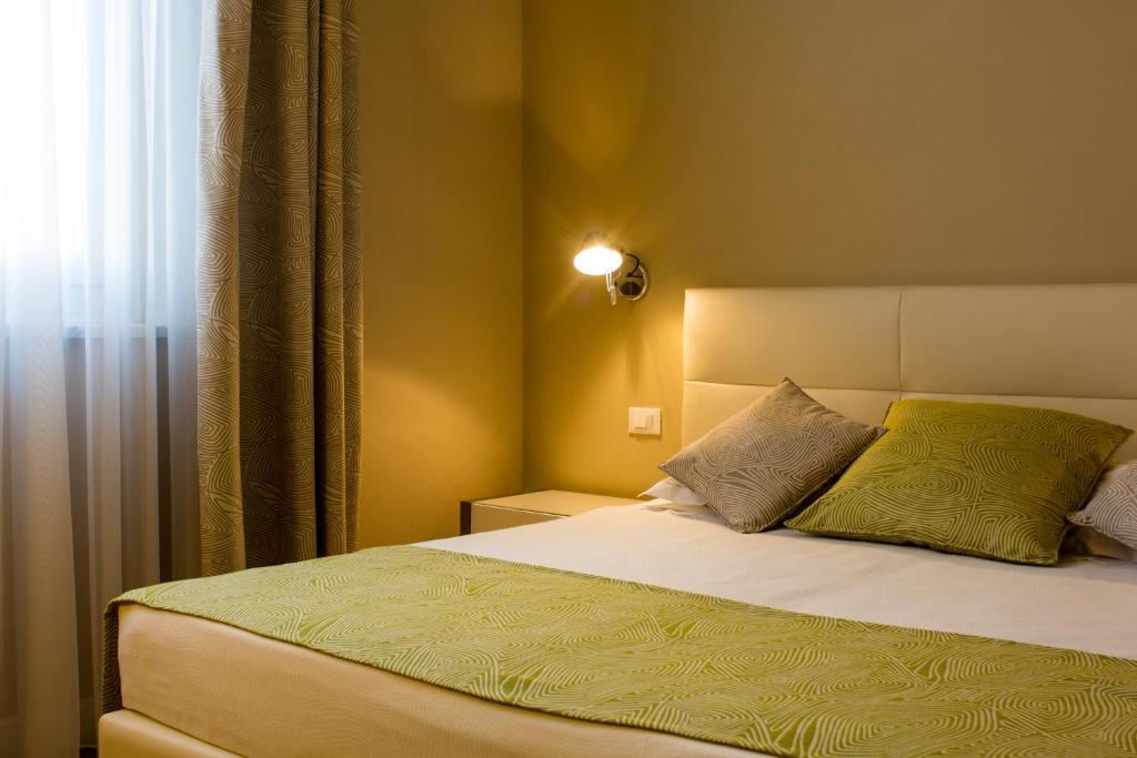 a bedroom with a bed with a yellow pillow at Hotel Universal in Livorno