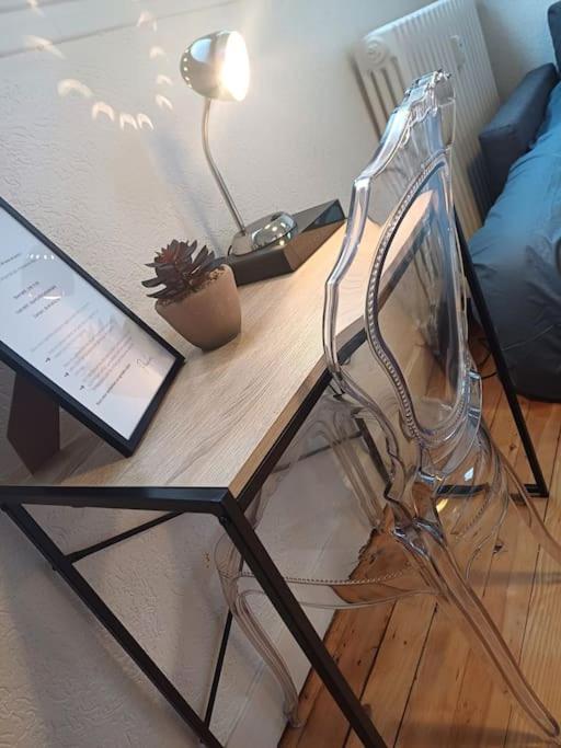 a glass chair sitting on top of a wooden table at Le Parvis - Vue Cathédrale - Plein Centre Ville in Beauvais