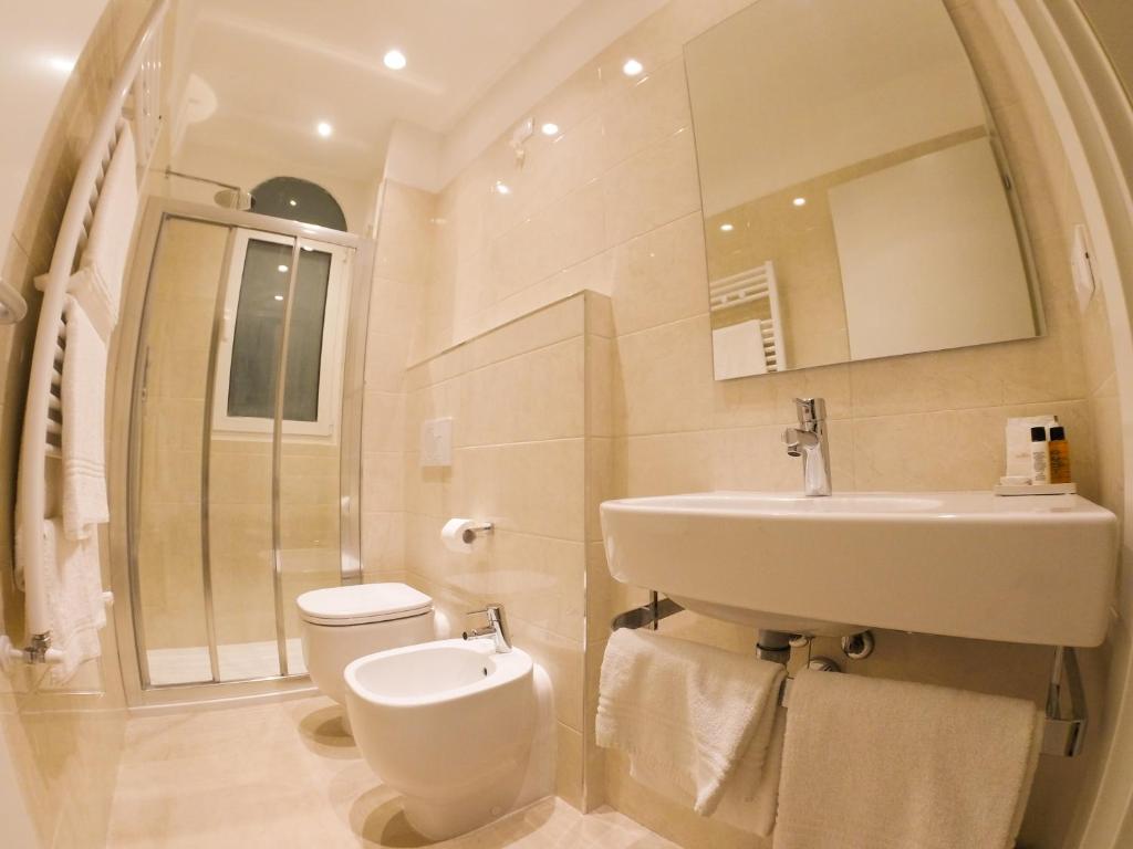 a white bathroom with a sink and a toilet at Hotel Universal in Livorno