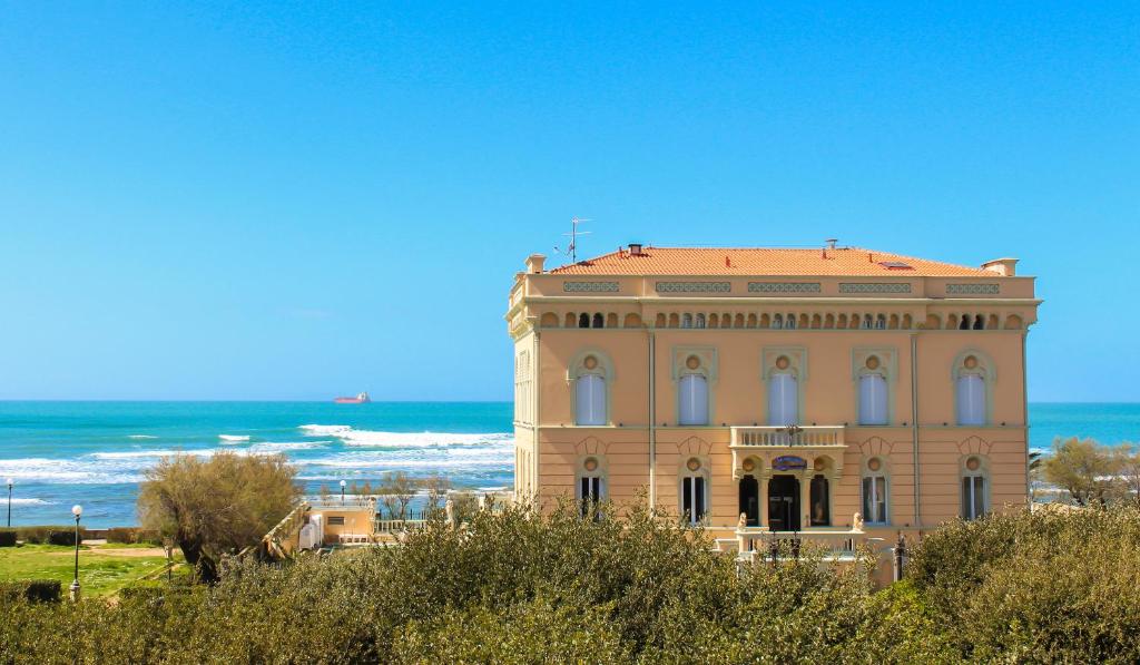a large building with the ocean in the background at Hotel Universal in Livorno