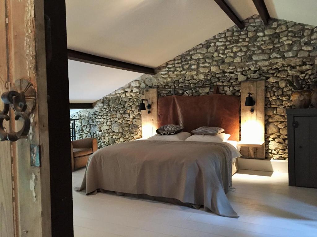 a bedroom with a large bed in a stone wall at Bassiviere Barn Chic in Saint-Étienne-de-Villeréal