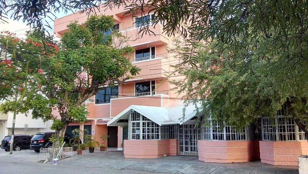 a pink building with a parking lot in front of it at Íkaro Suites Cancún in Cancún