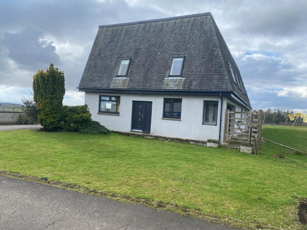 a white house with a black roof on a yard at Immaculate 2 Bed property in rural location in Alloa