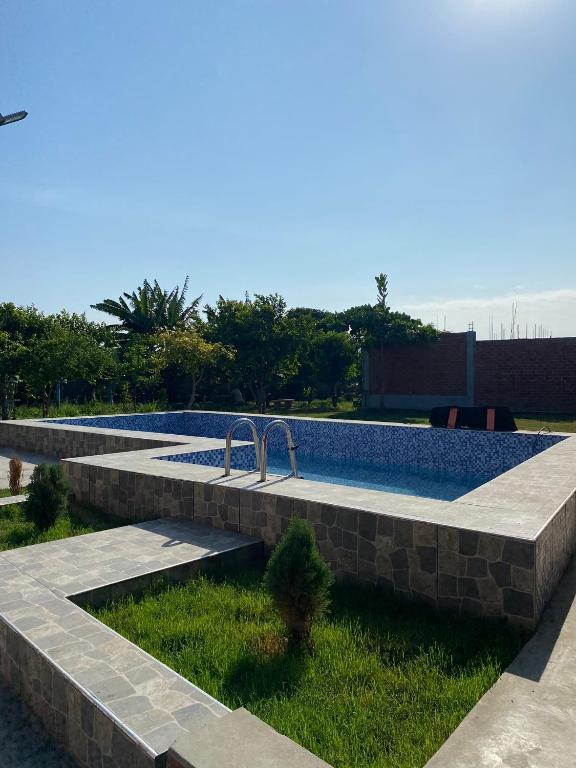 a stone retaining wall with a pool in a yard at Casa Polska in Paiján