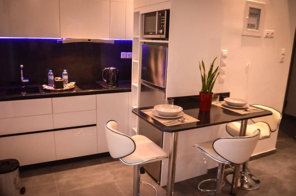 une cuisine avec des placards blancs et un comptoir avec des tabourets dans l'établissement Galaxyhome, à Athènes