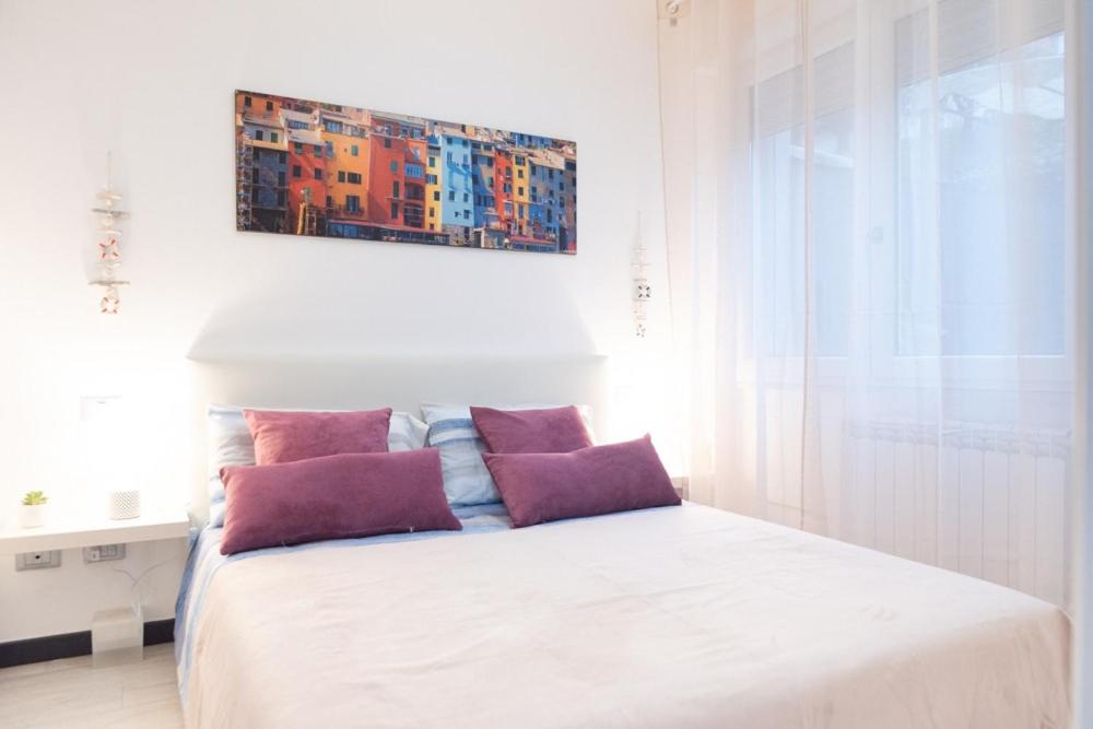 un letto bianco con cuscini viola in una camera da letto di la casa di gusto a La Spezia