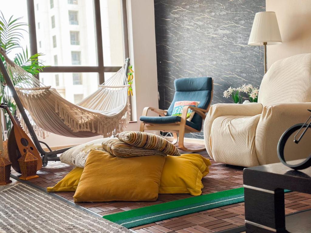 uma sala de estar com uma rede de descanso e uma cadeira em The Female Journey Hostel - JBR em Dubai