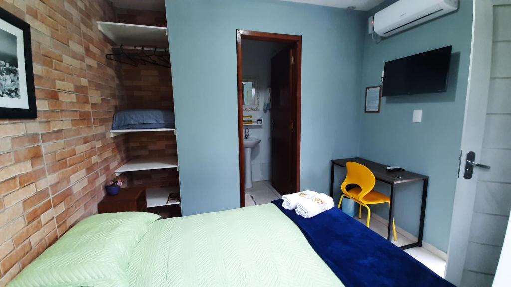 a bedroom with a bed and a brick wall at Pousada Casa da Maga - Centro in Blumenau