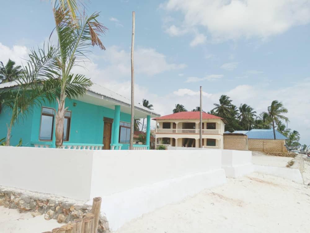 MINAZI BEACH BUNGALOWS في نونغوي: منزل على الشاطئ مع سياج أبيض