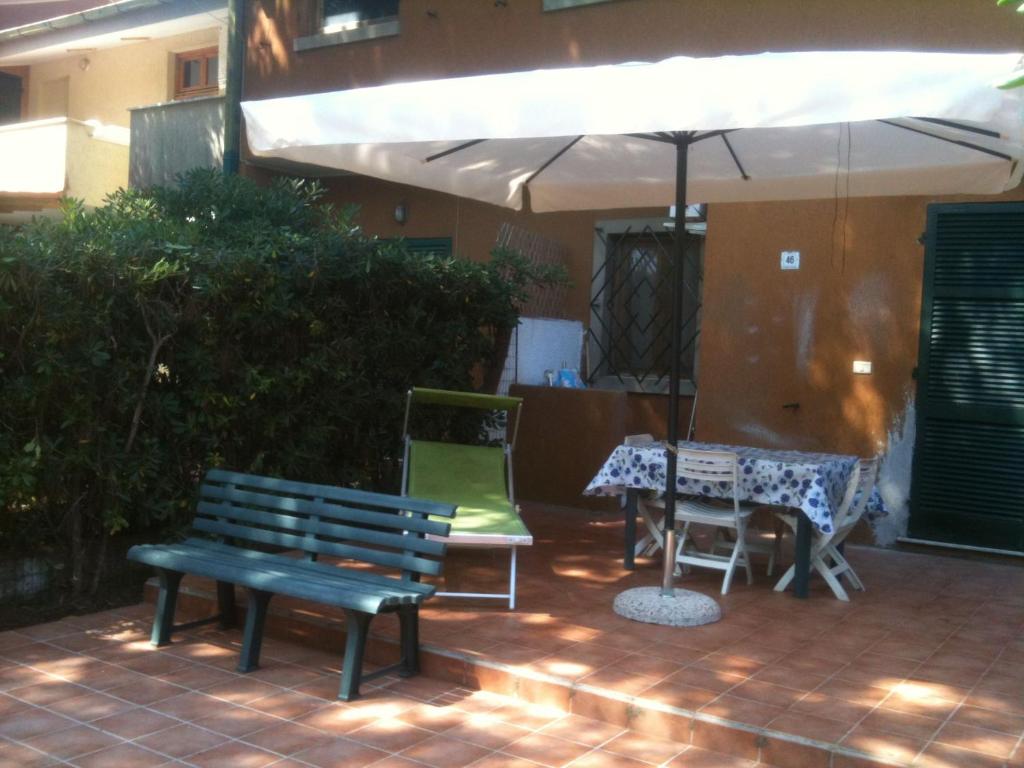 um pátio com dois bancos e uma mesa com um guarda-chuva em Residence Giannella - Pitosforo 46 em Giannella