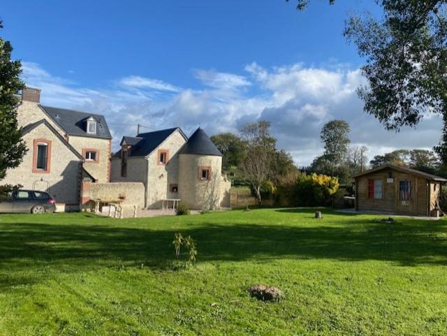 une grande maison dans un champ d'herbe verte dans l'établissement Plages du débarquement et bord de mer, à Grandcamp-Maisy